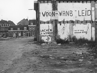 406951 Gezicht op de zijgevel van het pand Hoenderstraat 21, met de leuzen Woon-wanbeleid , Lachen / U wordt gefilmd en ...